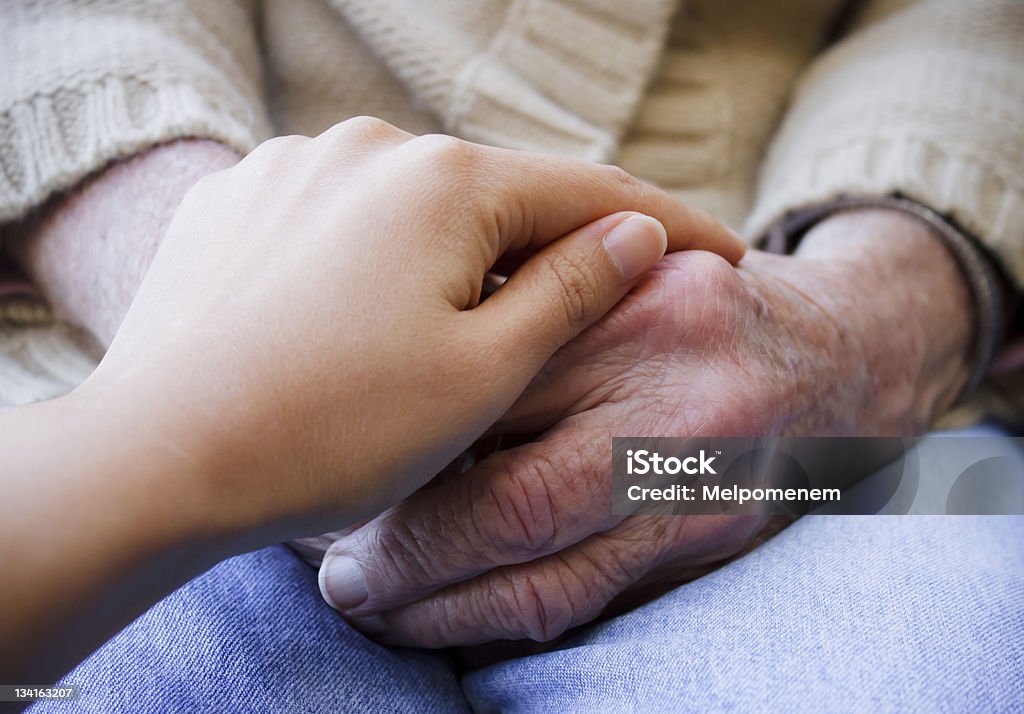 Joven holding senior manos - Foto de stock de 80-89 años libre de derechos