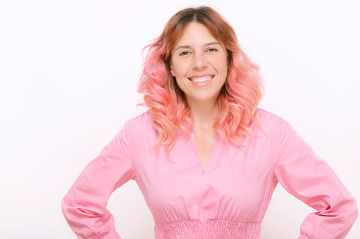 smiling mature woman with pink hair looking at camera wearing pink dress