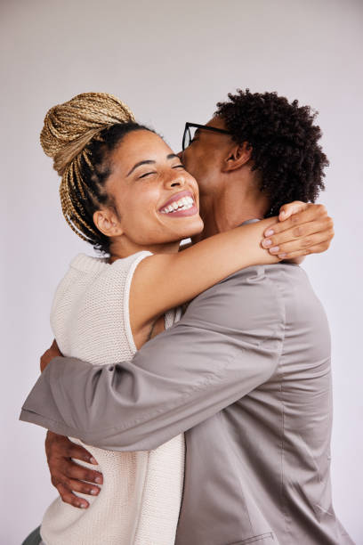 Laughing young woman hugging her boyfriend against a white background stock photo