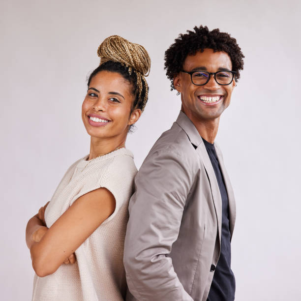 Smiling young businesspeople standing back to back against a white background stock photo
