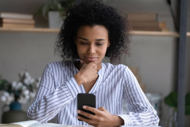 istock Young mixed race lady think on information on phone screen 1341644005