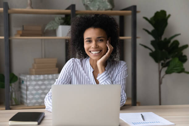 istock Mixed race female employee posing at work desk by laptop 1341644017
