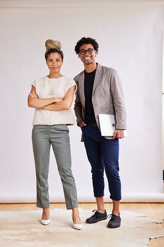 Portrait of two confident young African American businesspeople standing together and smiling in front of a white backdrop