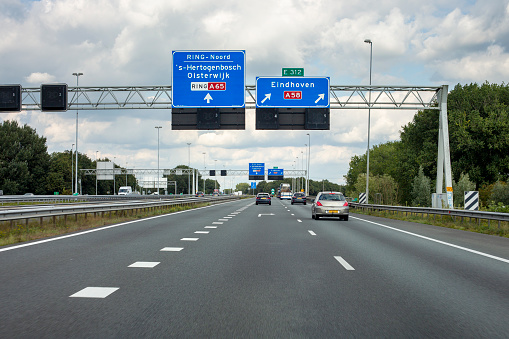 Tilburg, The Netherlands - September 16, 2021: Traffic on Dutch rijksweg A 58 nearby Knoppunt De Baars. The A58 motorway (Dutch: Rijksweg 58) is a motorway in the Netherlands. It connects North Brabant's three major cities Eindhoven, Tilburg and Breda with the cities Goes, Middelburg and Vlissingen in Zeeland. Some road users in the background.