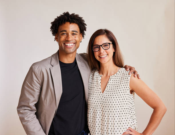 Two diverse young businesspeople standing arm in arm and smiling stock photo