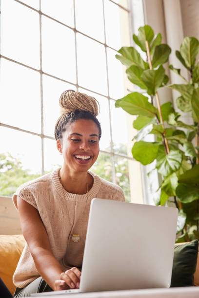 Smiling young businesswoman working on a laptop in an office lounge stock photo
