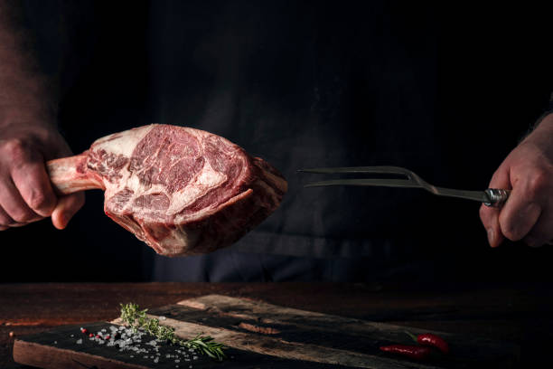 istock A man holds a Raw Tomahawk steak on a bone of dry aged beef on a dark background 1341649051
