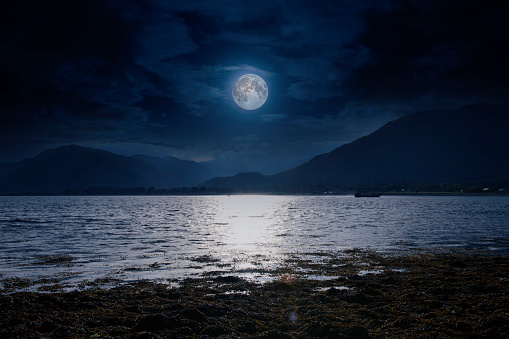 A composite image of a full moon over Loch Linnhe near Bunree in Glencoe, Scotland.