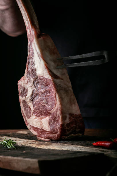 istock The chef's hands hold a raw Tomahawk a beef steak and a meat fork over a chopping Board 1341649077