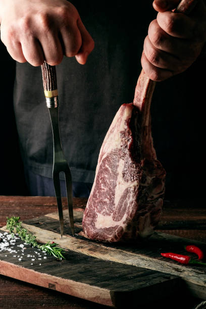 istock A man holds a Raw Tomahawk steak on a bone of dry aged beef on a dark background 1341649106