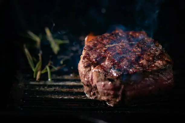 Photo of A steaming beef tenderloin steak is grilled in a grill pan with the text copy space. The concept of the recipe , filet Mignon