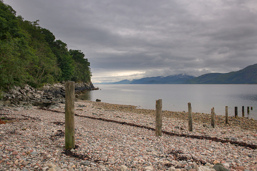 View from the beach at Bunree of low cloud drifting over mountains on the banks of Loch Linnhe in Glencoe, Scotland.