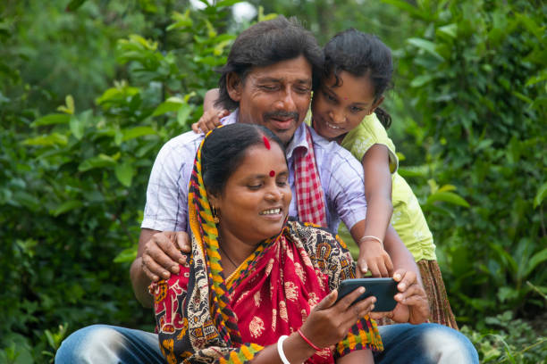 3 indian rural parents and daughter watching movie in agricultural field - asian country imagens e fotografias de stock