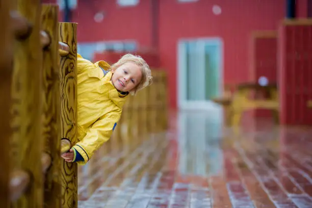 Cute child, enjoying little fishing village with rorbuer cabins on a heavy rainy day summertime