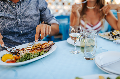 Young couple sitting at the table and enjoying seafood at outdoor restaurant during summer vacation