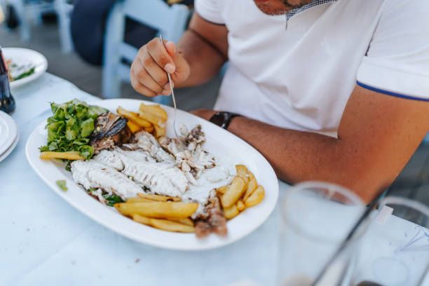 mężczyzna cieszący się morskimi potrawami w restauracji na świeżym powietrzu - fish and chips cafe restaurant salad zdjęcia i obrazy z banku zdjęć