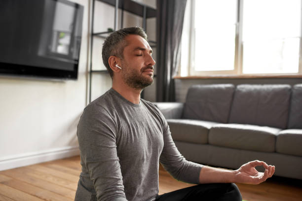 istock Calm man with eyes closed meditate at home 1341665322