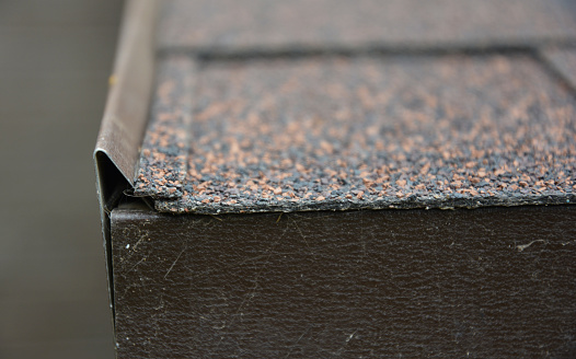 A close-up of a roofing asphalt shingle with a focus on the thickness of asphalt roofing material.