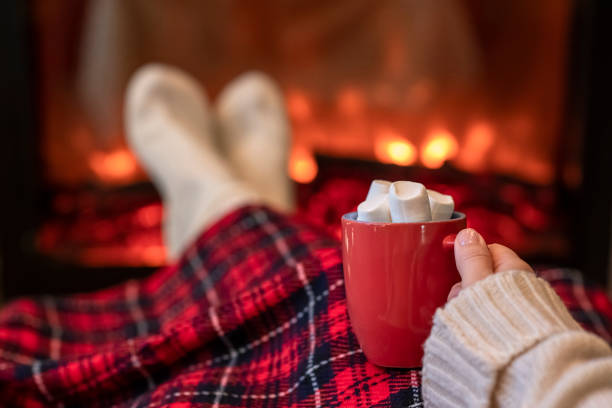 frau mit tasse heißen kakao und marshmallow wärmende beine in winter weiße socken in der nähe von kamin flamme, bedeckt weihnachten kariert - behaglich stock-fotos und bilder