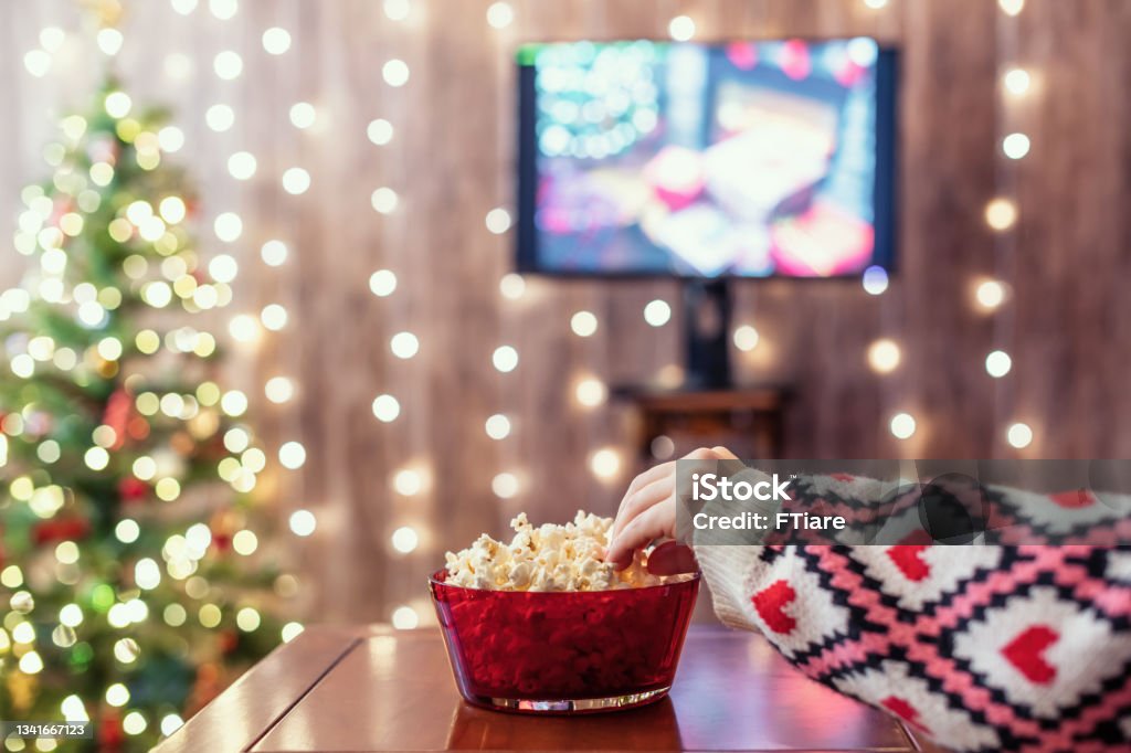 Christmas eve. Alone woman watching tv and eating popcorn. Home cinema. Cropped, close up Christmas Stock Photo