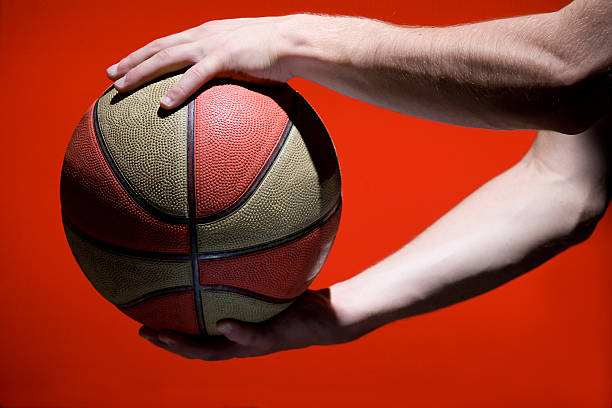 istock Basketball ball in hands isolated on red background 134166744