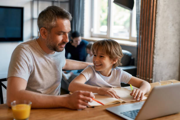 istock Smiling teen boy child study online on computer with dad 1341669208
