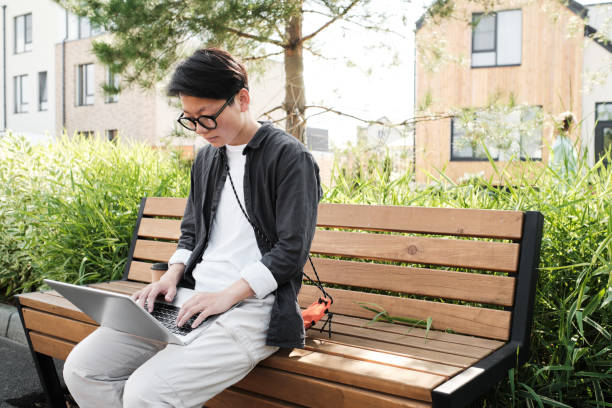 istock Asian Woman Using Laptop Outdoors 1341670241