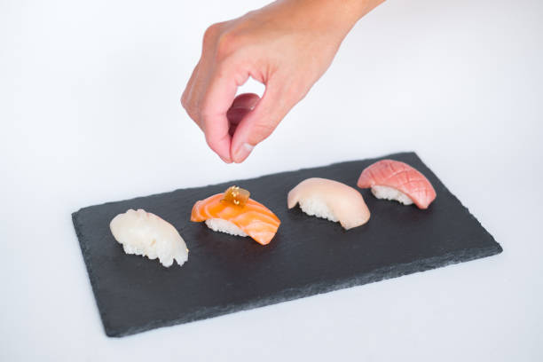 istock Four sushi pieces served on black slate on the white background. 1341670566