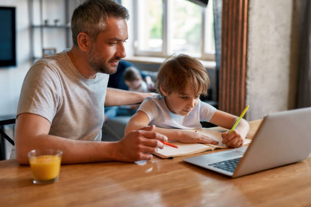 istock Father help teen son with school homework online 1341672036