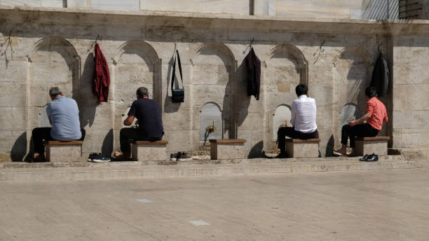 muslimische männer nehmen rituelle waschung in wudhu station in moschee in istanbul - september, 2021. wasserhähne zum waschen von händen und füßen vor dem gebet und steine zum sitzen in der nähe der moschee in der islamischen kultur. - istanbul people faucet turkey stock-fotos und bilder