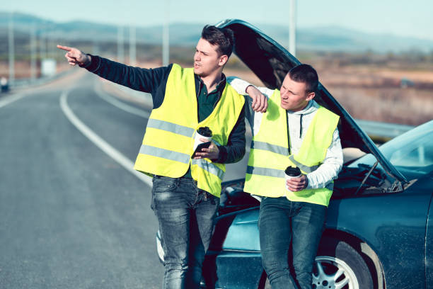 dois homens com coletes de segurança bebendo café enquanto esperam por ajuda de carro quebrado na estrada - acidente evento relacionado com o transporte - fotografias e filmes do acervo