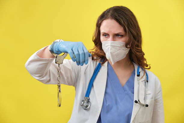 istock Doctor with a scared face in a medical uniform and handcuffs 1341679648