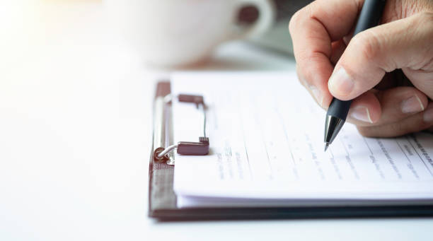 Close-up of Hand using writing pen with questionnaire or paperwork survey question filling. Close-up of Hand using writing pen with questionnaire or paperwork survey question filling in business company personal information form checklist document. form filling stock pictures, royalty-free photos & images