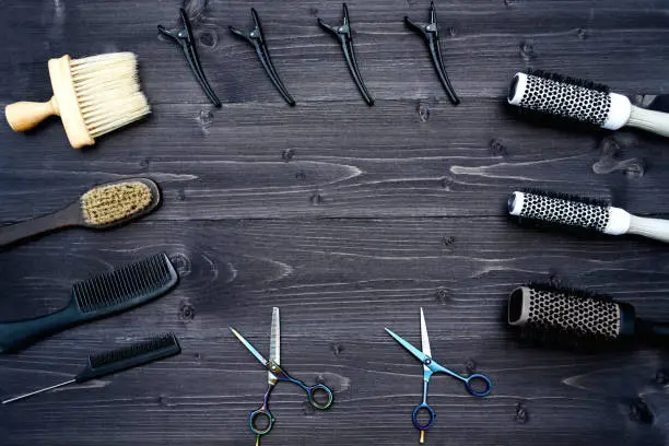 Hairdresser tools on wooden background. Top view on wooden table with scissors, comb, hairbrushes and hairclips, free space