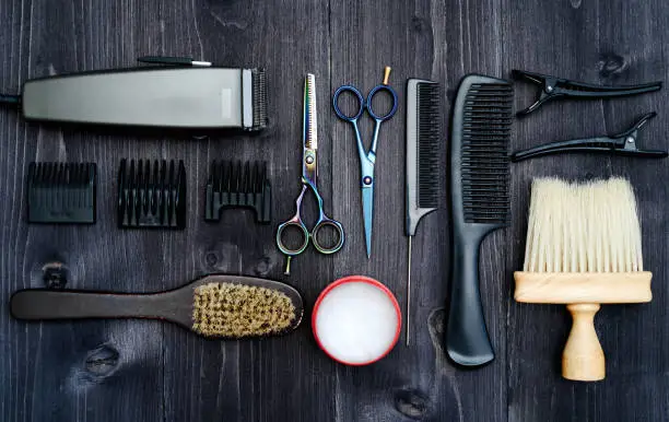 Hairdresser tools on wooden background. Top view on wooden table with scissors, comb, hairbrushes and hairclips, free space. Barbershop, manhood concept