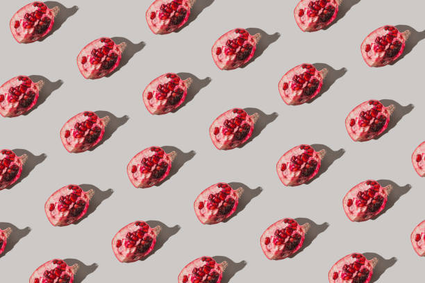 istock Creative pattern made of fresh slices of pomegranate on pastel grey background with sunlit. Minimal style. Top view. Flat lay . 1341684959