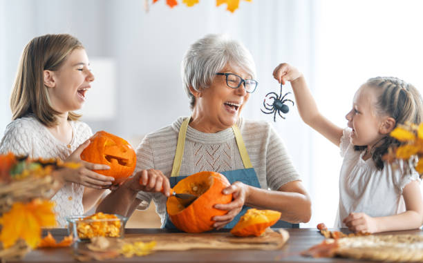 family preparing for Halloween Happy family preparing for Halloween. Grandmother and granddaughter carving pumpkins at home. carving food photos stock pictures, royalty-free photos & images