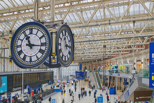 London Waterloo railway station, England, UK - a close-up of the famous four sided clock at Waterloo station with a crowd of passengers waiting for trains beneath it on the main councourse