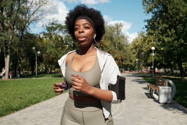 istock Active woman listening to music while training in park 1341688141