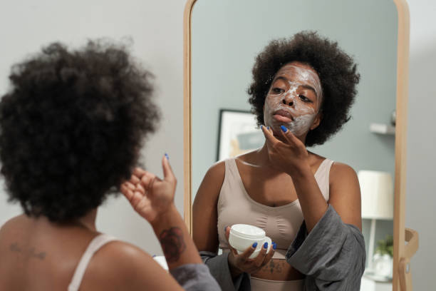 istock Young female applying mask on face in front of mirror 1341688168