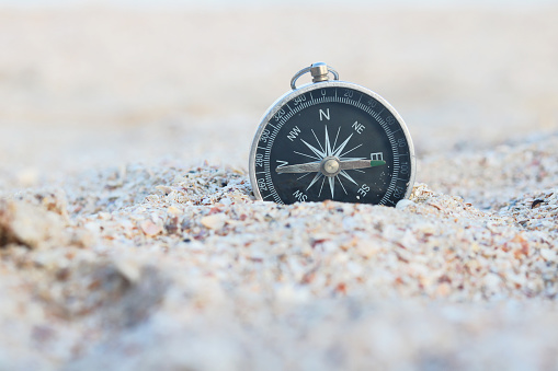 Classic navigation compass on beach as symbol of tourism with compass, travel with compass and outdoor activities with compass