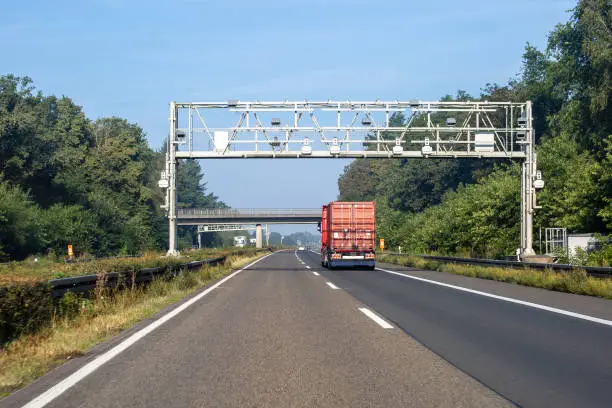 A truck on german Autobahn A 57 passes a toll gantry of LKW Maut (HGV toll, lorry toll)