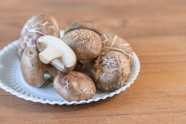Group Shiitake mushrooms on dish on wooden background.