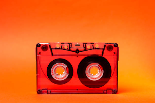 istock Compact cassette. Audio cassette or compact cassette b on an orange background. Previously, it was one of the most common storage media on magnetic tape. 1341693576