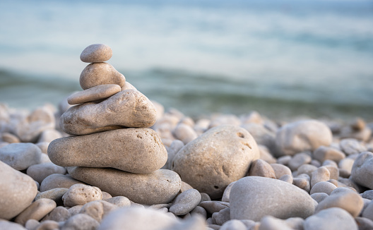 An image of several stones stacked and balanced carefully with the blue Pacific Ocean in the background.