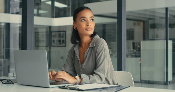 scatto di una bella giovane donna persa nei pensieri mentre usa il suo laptop in un ufficio moderno - thinking women businesswoman business foto e immagini stock