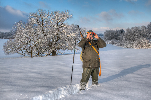 happy smiling sporty 45 years old woman in winter sport outdoor clothes snowshoeing walking in deep fresh snow on cold sunny day in beautiful winterly landscape with snowcovered trees and sunshine