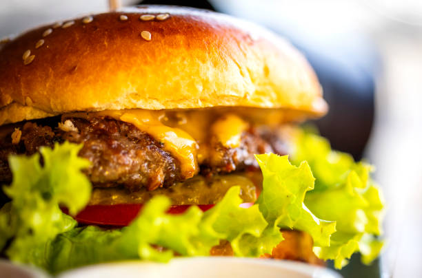 Hamburger close up view Delicious Hamburger with cheese and french fries on wooden table and bright background burger close up stock pictures, royalty-free photos & images