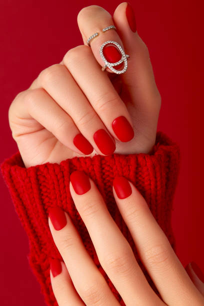 istock Female hands with manicure in sweater. Red matt nail design 1341698532