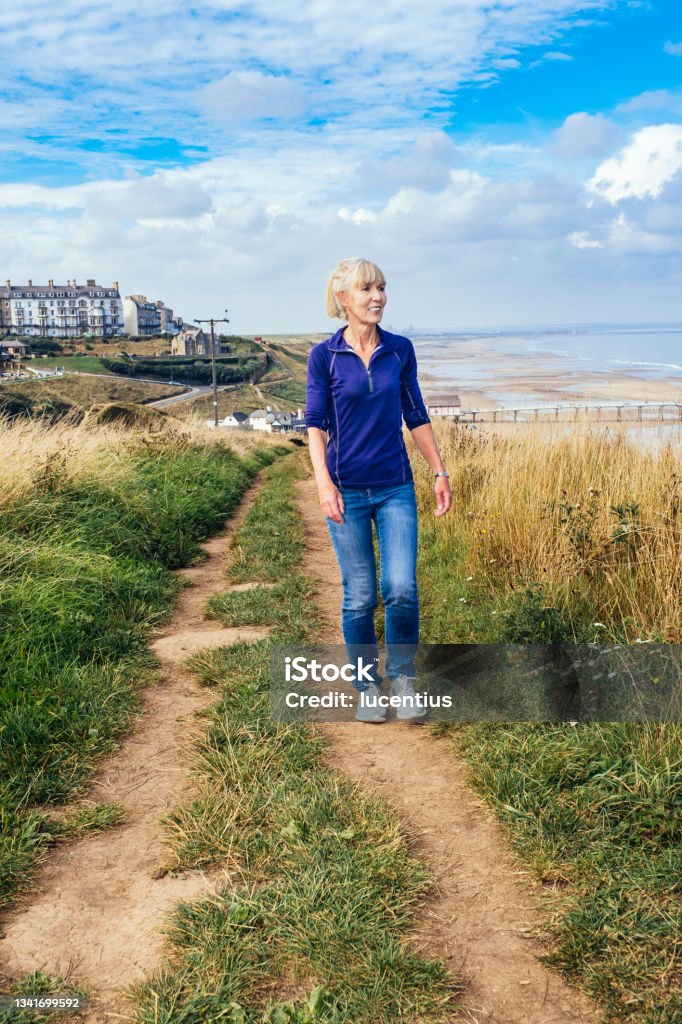 Cleveland Way footpath above Saltburn, England Woman walking the Cleveland Way long distance footpath above the village of Saltburn, North Yorkshire Region, England. 50-59 Years Stock Photo